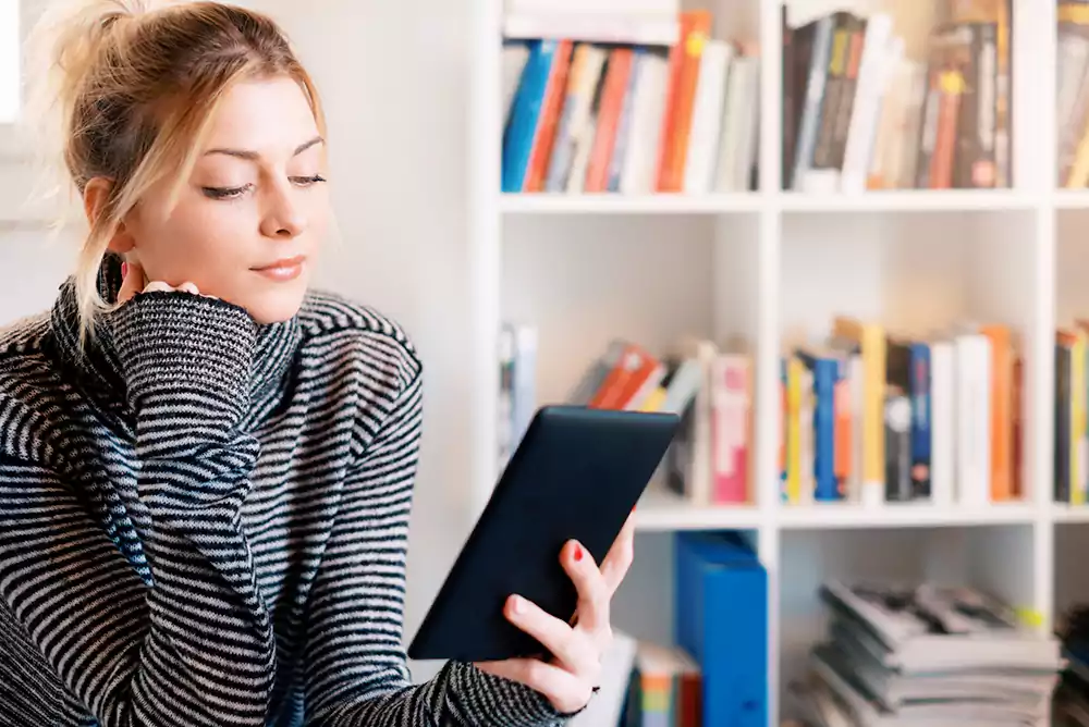 Mulher com tablet na mão lendo um e-book